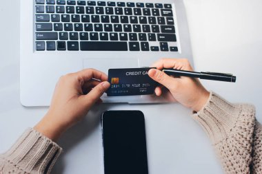 Kapanmış adam dizüstü bilgisayarı kullan kredi kartı kullan cep telefonu kullan kahve dükkanında masaya otur, dinlenme dinlenme dinlenme dinlenme dinlenme boş zamanlarında serbest mobil konsepte odaklan nesneye odaklan