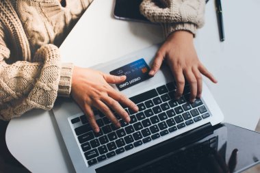 Kapanmış adam dizüstü bilgisayarı kullan kredi kartı kullan cep telefonu kullan kahve dükkanında masaya otur, dinlenme dinlenme dinlenme dinlenme dinlenme boş zamanlarında serbest mobil konsepte odaklan nesneye odaklan