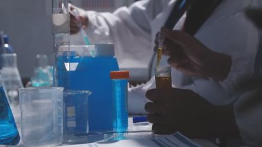 Tıbbi ya da bilimsel araştırmacı ya da insan doktoru laboratuarda bir test tüpü dolusu temiz çözeltiye bakıyor.