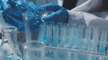 Tıbbi ya da bilimsel araştırmacı ya da insan doktoru laboratuarda bir test tüpü dolusu temiz çözeltiye bakıyor.