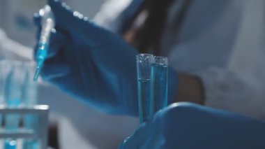 Tıbbi ya da bilimsel araştırmacı ya da insan doktoru laboratuarda bir test tüpü dolusu temiz çözeltiye bakıyor.