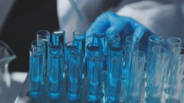 Tıbbi ya da bilimsel araştırmacı ya da insan doktoru laboratuarda bir test tüpü dolusu temiz çözeltiye bakıyor.