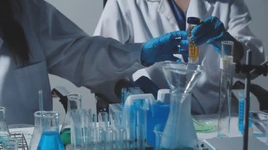 Tıbbi ya da bilimsel araştırmacı ya da insan doktoru laboratuarda bir test tüpü dolusu temiz çözeltiye bakıyor.