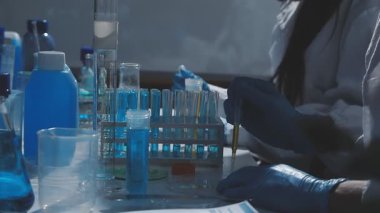 Tıbbi ya da bilimsel araştırmacı ya da insan doktoru laboratuarda bir test tüpü dolusu temiz çözeltiye bakıyor.