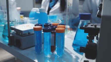 Tıbbi ya da bilimsel araştırmacı ya da insan doktoru laboratuarda bir test tüpü dolusu temiz çözeltiye bakıyor.