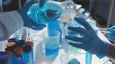 Tıbbi ya da bilimsel araştırmacı ya da insan doktoru laboratuarda bir test tüpü dolusu temiz çözeltiye bakıyor.