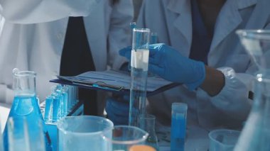 Tıbbi ya da bilimsel araştırmacı ya da insan doktoru laboratuarda bir test tüpü dolusu temiz çözeltiye bakıyor.