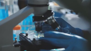 Tıbbi ya da bilimsel araştırmacı ya da insan doktoru laboratuarda bir test tüpü dolusu temiz çözeltiye bakıyor.