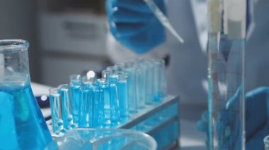 Tıbbi ya da bilimsel araştırmacı ya da insan doktoru laboratuarda bir test tüpü dolusu temiz çözeltiye bakıyor.