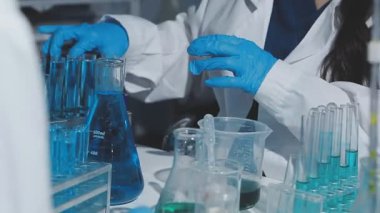 Tıbbi ya da bilimsel araştırmacı ya da insan doktoru laboratuarda bir test tüpü dolusu temiz çözeltiye bakıyor.