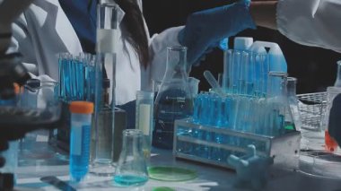 Tıbbi ya da bilimsel araştırmacı ya da insan doktoru laboratuarda bir test tüpü dolusu temiz çözeltiye bakıyor.