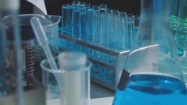 Tıbbi ya da bilimsel araştırmacı ya da insan doktoru laboratuarda bir test tüpü dolusu temiz çözeltiye bakıyor.