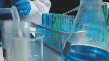 Tıbbi ya da bilimsel araştırmacı ya da insan doktoru laboratuarda bir test tüpü dolusu temiz çözeltiye bakıyor.