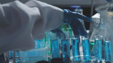 Tıbbi ya da bilimsel araştırmacı ya da insan doktoru laboratuarda bir test tüpü dolusu temiz çözeltiye bakıyor.