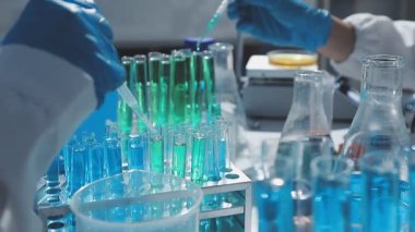 Tıbbi ya da bilimsel araştırmacı ya da insan doktoru laboratuarda bir test tüpü dolusu temiz çözeltiye bakıyor.