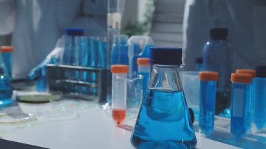 Tıbbi ya da bilimsel araştırmacı ya da insan doktoru laboratuarda bir test tüpü dolusu temiz çözeltiye bakıyor.