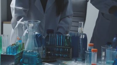 Tıbbi ya da bilimsel araştırmacı ya da insan doktoru laboratuarda bir test tüpü dolusu temiz çözeltiye bakıyor.