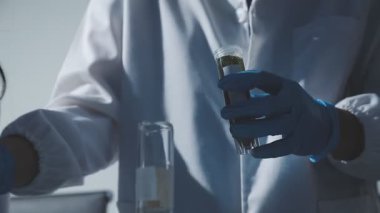 Tıbbi ya da bilimsel araştırmacı ya da insan doktoru laboratuarda bir test tüpü dolusu temiz çözeltiye bakıyor.