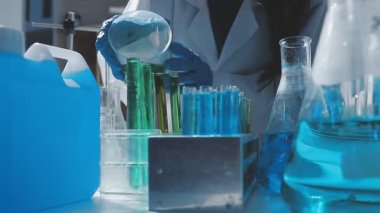 Tıbbi ya da bilimsel araştırmacı ya da insan doktoru laboratuarda bir test tüpü dolusu temiz çözeltiye bakıyor.