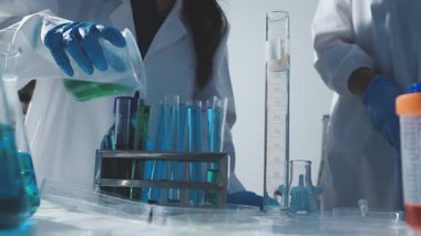 Tıbbi ya da bilimsel araştırmacı ya da insan doktoru laboratuarda bir test tüpü dolusu temiz çözeltiye bakıyor.