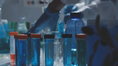 Tıbbi ya da bilimsel araştırmacı ya da insan doktoru laboratuarda bir test tüpü dolusu temiz çözeltiye bakıyor.