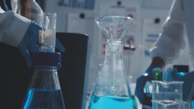 Tıbbi ya da bilimsel araştırmacı ya da insan doktoru laboratuarda bir test tüpü dolusu temiz çözeltiye bakıyor.