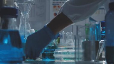 Tıbbi ya da bilimsel araştırmacı ya da insan doktoru laboratuarda bir test tüpü dolusu temiz çözeltiye bakıyor.