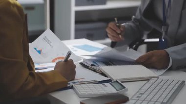 Ofiste çalışan denetçi ve muhasebeci ekibi mali verileri ve muhasebe kayıtlarını hesap makinesiyle analiz ediyor. Muhasebe şirketi kârlı nakit akışı için finansman ve vergilendirme planlaması sağlıyor