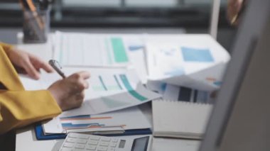 Ofiste çalışan denetçi ve muhasebeci ekibi mali verileri ve muhasebe kayıtlarını hesap makinesiyle analiz ediyor. Muhasebe şirketi kârlı nakit akışı için finansman ve vergilendirme planlaması sağlıyor