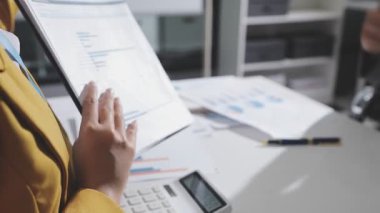 Ofiste çalışan denetçi ve muhasebeci ekibi mali verileri ve muhasebe kayıtlarını hesap makinesiyle analiz ediyor. Muhasebe şirketi kârlı nakit akışı için finansman ve vergilendirme planlaması sağlıyor