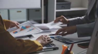 Ofiste çalışan denetçi ve muhasebeci ekibi mali verileri ve muhasebe kayıtlarını hesap makinesiyle analiz ediyor. Muhasebe şirketi kârlı nakit akışı için finansman ve vergilendirme planlaması sağlıyor