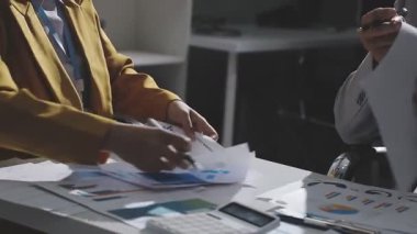 Ofiste çalışan denetçi ve muhasebeci ekibi mali verileri ve muhasebe kayıtlarını hesap makinesiyle analiz ediyor. Muhasebe şirketi kârlı nakit akışı için finansman ve vergilendirme planlaması sağlıyor