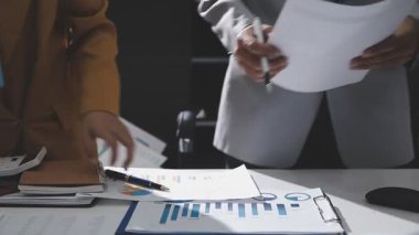 Ofiste çalışan denetçi ve muhasebeci ekibi mali verileri ve muhasebe kayıtlarını hesap makinesiyle analiz ediyor. Muhasebe şirketi kârlı nakit akışı için finansman ve vergilendirme planlaması sağlıyor