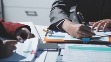 Ofiste çalışan denetçi ve muhasebeci ekibi mali verileri ve muhasebe kayıtlarını hesap makinesiyle analiz ediyor. Muhasebe şirketi kârlı nakit akışı için finansman ve vergilendirme planlaması sağlıyor