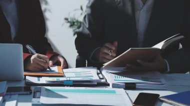 Ofiste çalışan denetçi ve muhasebeci ekibi mali verileri ve muhasebe kayıtlarını hesap makinesiyle analiz ediyor. Muhasebe şirketi kârlı nakit akışı için finansman ve vergilendirme planlaması sağlıyor