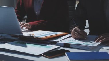 Ofiste çalışan denetçi ve muhasebeci ekibi mali verileri ve muhasebe kayıtlarını hesap makinesiyle analiz ediyor. Muhasebe şirketi kârlı nakit akışı için finansman ve vergilendirme planlaması sağlıyor