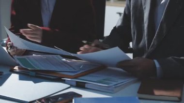 Ofiste çalışan denetçi ve muhasebeci ekibi mali verileri ve muhasebe kayıtlarını hesap makinesiyle analiz ediyor. Muhasebe şirketi kârlı nakit akışı için finansman ve vergilendirme planlaması sağlıyor