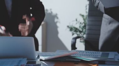 Ofiste çalışan denetçi ve muhasebeci ekibi mali verileri ve muhasebe kayıtlarını hesap makinesiyle analiz ediyor. Muhasebe şirketi kârlı nakit akışı için finansman ve vergilendirme planlaması sağlıyor