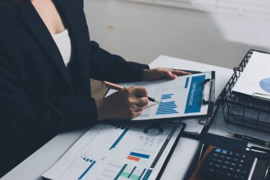 Modern ofiste işbirliği yapan denetçiler, finansal belgeleri analiz ediyorlar ve çizelgeleri gösteren bir dizüstü bilgisayarla hesap makinesi kullanıyorlar. Ticarette denetim ve vergiler