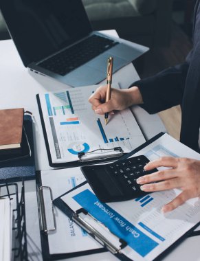 Modern ofiste işbirliği yapan denetçiler, finansal belgeleri analiz ediyorlar ve çizelgeleri gösteren bir dizüstü bilgisayarla hesap makinesi kullanıyorlar. Ticarette denetim ve vergiler