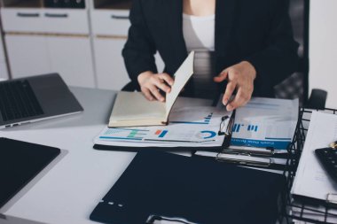 Modern ofiste işbirliği yapan denetçiler, finansal belgeleri analiz ediyorlar ve çizelgeleri gösteren bir dizüstü bilgisayarla hesap makinesi kullanıyorlar. Ticarette denetim ve vergiler