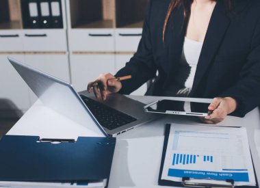 Modern ofiste işbirliği yapan denetçiler, finansal belgeleri analiz ediyorlar ve çizelgeleri gösteren bir dizüstü bilgisayarla hesap makinesi kullanıyorlar. Ticarette denetim ve vergiler