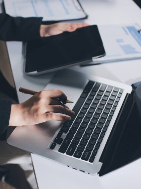 Modern ofiste işbirliği yapan denetçiler, finansal belgeleri analiz ediyorlar ve çizelgeleri gösteren bir dizüstü bilgisayarla hesap makinesi kullanıyorlar. Ticarette denetim ve vergiler