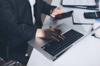 Modern ofiste işbirliği yapan denetçiler, finansal belgeleri analiz ediyorlar ve çizelgeleri gösteren bir dizüstü bilgisayarla hesap makinesi kullanıyorlar. Ticarette denetim ve vergiler