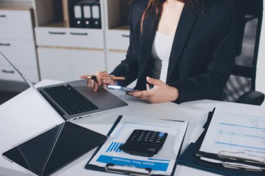 Modern ofiste işbirliği yapan denetçiler, finansal belgeleri analiz ediyorlar ve çizelgeleri gösteren bir dizüstü bilgisayarla hesap makinesi kullanıyorlar. Ticarette denetim ve vergiler