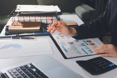 Modern ofiste işbirliği yapan denetçiler, finansal belgeleri analiz ediyorlar ve çizelgeleri gösteren bir dizüstü bilgisayarla hesap makinesi kullanıyorlar. Ticarette denetim ve vergiler