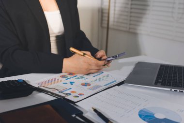 Modern ofiste işbirliği yapan denetçiler, finansal belgeleri analiz ediyorlar ve çizelgeleri gösteren bir dizüstü bilgisayarla hesap makinesi kullanıyorlar. Ticarette denetim ve vergiler