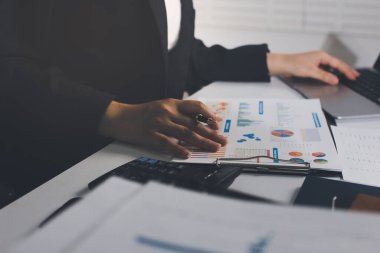 Modern ofiste işbirliği yapan denetçiler, finansal belgeleri analiz ediyorlar ve çizelgeleri gösteren bir dizüstü bilgisayarla hesap makinesi kullanıyorlar. Ticarette denetim ve vergiler