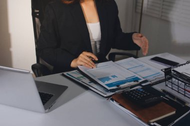 Modern ofiste işbirliği yapan denetçiler, finansal belgeleri analiz ediyorlar ve çizelgeleri gösteren bir dizüstü bilgisayarla hesap makinesi kullanıyorlar. Ticarette denetim ve vergiler