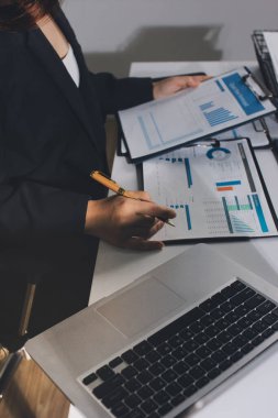 Modern ofiste işbirliği yapan denetçiler, finansal belgeleri analiz ediyorlar ve çizelgeleri gösteren bir dizüstü bilgisayarla hesap makinesi kullanıyorlar. Ticarette denetim ve vergiler